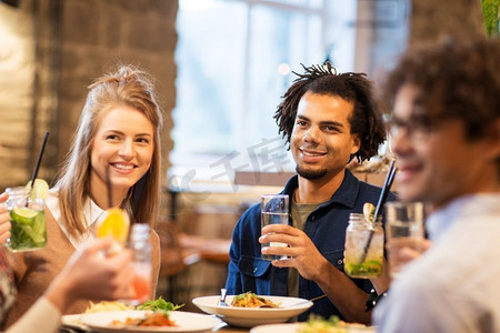 休闲和人际概念—快乐的朋友在酒吧或餐馆吃和喝不含酒精的饮料。快乐的朋友在酒吧或餐馆吃饭