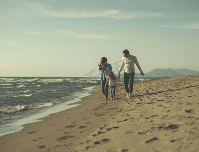 年轻的家庭在秋日里享受着矢量。秋天，一家人带着小女儿在海滩上休息和玩耍，彩色滤镜