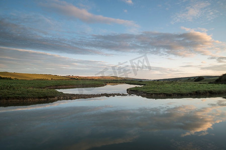 美丽的日出风景在英国乡村与河慢慢流过田野