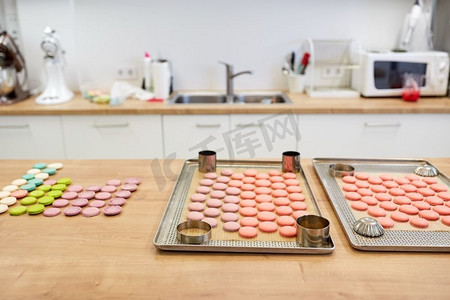盘龙摄影照片_烹调，糖果和烘烤概念-在烤箱盘的马卡龙在面包店或糕点店厨房。糖果店的烤箱托盘上的马卡龙