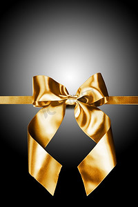 黑色上的金色礼物蝴蝶结。黑色背景上的金色彩带蝴蝶结
