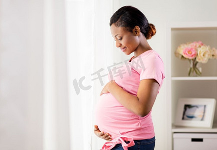 怀孕、人和期望概念-有大肚子的愉快的怀孕的非洲裔美国妇女在家。快乐的孕妇与大肚子在家里