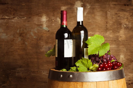 酒窖背景摄影照片_橡木桶上的一瓶瓶葡萄酒覆盖着破旧的木质背景。几瓶葡萄酒