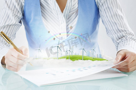 替代能源概念。女实业家写作近景与钢笔和风力发电机在纸上