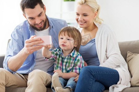家庭、技术和人的概念-快乐的母亲、父亲和家里有智能手机的小男孩。家里有智能手机，幸福的家庭