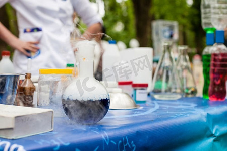 桌子上放着各种化学器皿。前面是一个烧瓶，里面有化学反应。科学化学实验