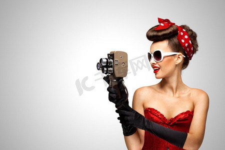 复古电影风格..一个海报女孩的复古照片与一个老葡萄酒8毫米照相机在灰色背景。