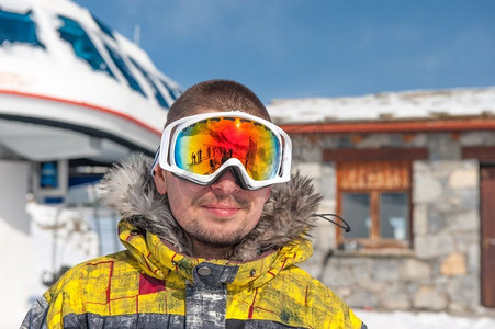 戴着滑雪护目镜的年轻人在户外，背景是山上的滑雪缆车站。Vald&rsquo；伊斯雷尔，法国