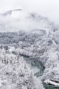 冬季景观积雪覆盖树木，火车过河过桥