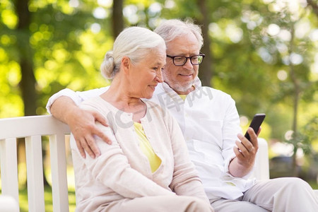 手机夏季夏季摄影照片_老年、科技和人的概念快乐的老年夫妇在夏季公园拿着智能手机。快乐的高年级夫妇在公园里拿着智能手机