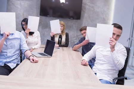 创业办公室里一个年轻的商业团队用白纸遮住脸的肖像