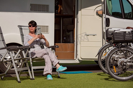 一位女士站在露营车附近，手里拿着一杯咖啡。大篷车度假。家庭度假旅行，开着房车度假旅行