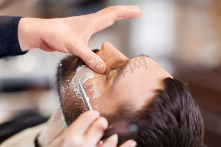 美容和人的概念-理发店里留着直剃刀胡子的男人和理发师。留着直剃须刀的男人和理发师