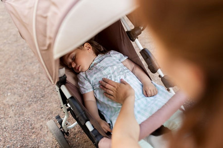 家庭、母亲和人的概念-母亲和孩子睡在婴儿车里。母亲带着孩子睡在婴儿车里