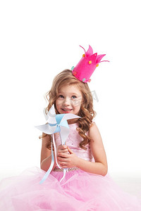 有风车的公主女孩。美丽的糖果小公主，戴着皇冠，手持风车，微笑着