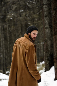 冬天森林里的一个人很冷，穿着棕色外套，戴着手套