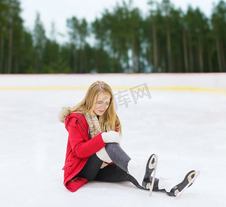 体育、创伤和冬天概念-有遭受痛苦的膝盖受伤的少妇在溜冰场。年轻女子在溜冰场膝盖受伤