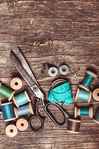 线裁缝摄影照片_木桌上的复古剪刀、纺织品和缝纫线。蓝色复古缝纫