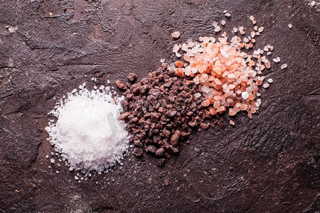 各种盐类，粉色喜马拉雅山脉和黑色与海盐的板岩背景。各种类型的盐类