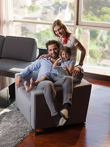 幸福年轻的一家人坐在沙发上一起玩平板电脑