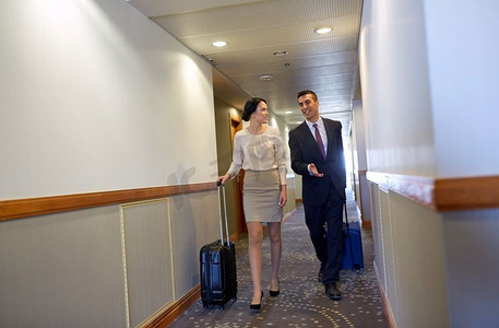 商务旅行和人的概念-男人和女人在酒店走廊上提着旅行包。商务团队带着旅行包在酒店走廊