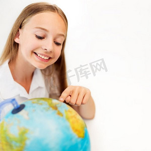 教育摄影照片_教育、地理、旅行和人概念-有地球仪的微笑的学生女孩。微笑的学生女孩与地球仪