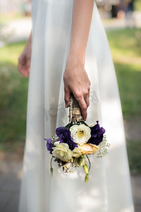 抱花的摄影照片_新娘手持印有紫色花朵的结婚花束