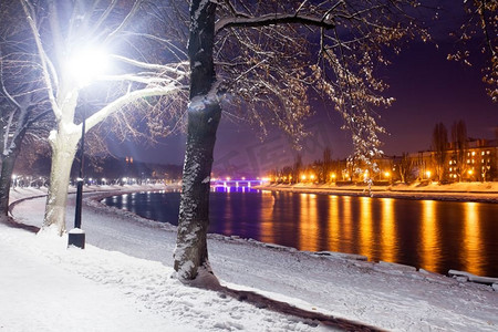 冷行人摄影照片_晚城白雪覆盖的堤岸。美丽的冬季风景。白雪覆盖的堤坝夜景