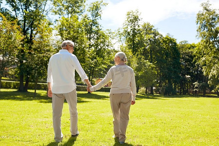 老年、关系和人的概念--快乐的老年夫妇在夏日城市公园散步。快乐的高年级夫妇在夏日城市公园散步