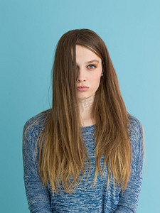 一位美丽积极的年轻女子一边玩耍着蓝色背景下孤立的丝质长发