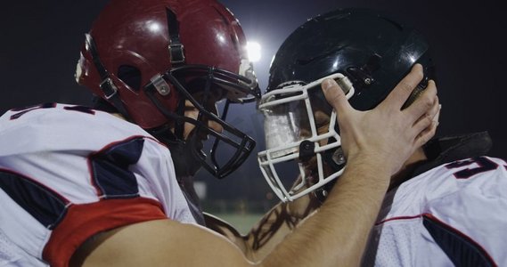 开心驾驶摄影照片_美国橄榄球运动员玩得开心，戴着头盔互相撞击