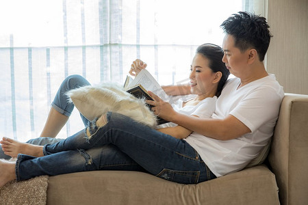 分享读书摄影照片_年轻夫妇在当代住宅客厅里一起读书，分享生活方式理念