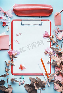 夹子边框摄影照片_写字台的俯视图，有剪贴板，配件和花朵，蓝色背景，边框。。工作空间平铺