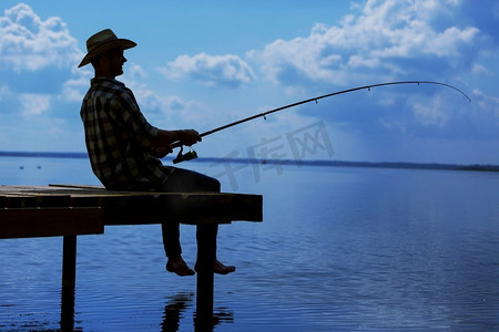 夏季钓鱼年轻人在帽子坐在桥和钓鱼