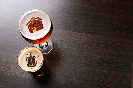 本地精酿啤酒。本地精酿啤酒。在酒吧桌子上的两杯鲜啤酒中，房子和心脏的轮廓，从上面看