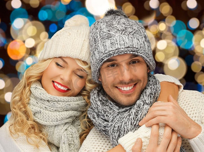 戴头饰的女人摄影照片_圣诞节、节假日和人们概念快乐的情侣戴着冬帽在灯光下。戴着帽子的幸福夫妇在灯光的背景下