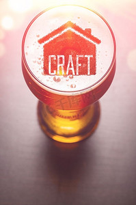 本地精酿啤酒。酒吧桌上一杯新鲜啤酒中的房子剪影，从高处俯瞰。本地精酿啤酒