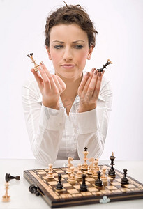 象棋游戏摄影照片_年轻迷人的女商人下着象棋
