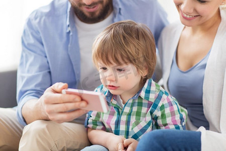 家庭、技术和人的概念-快乐的母亲、父亲和家里有智能手机的小男孩。家里有智能手机，幸福的家庭