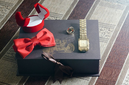 成婚摄影照片_手表、戒指、蝴蝶饰品新郎，躺在盒子上