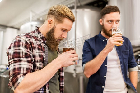酒精生产、商业和人的概念-男人在啤酒厂饮用和测试精酿啤酒。在酿酒厂饮用和测试精酿啤酒的男子