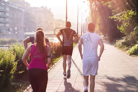 在城市里阳光明媚的早晨，一群运动健壮的年轻人在慢跑