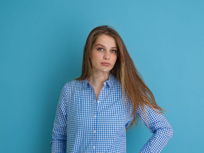 丝质摄影照片_一位美丽积极的年轻女子一边玩耍着蓝色背景下孤立的丝质长发