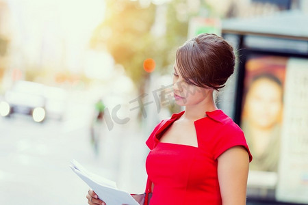 外面是女商人的肖像。身穿红色连衣裙的女商人手持文件的肖像