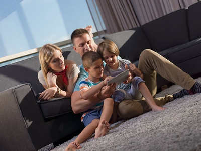 幸福年轻的一家人坐在沙发上一起玩平板电脑