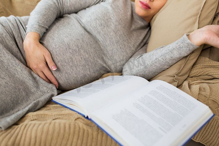 怀孕，人和母亲的概念-特写孕妇睡在家里的书。孕妇抱着书睡觉的特写