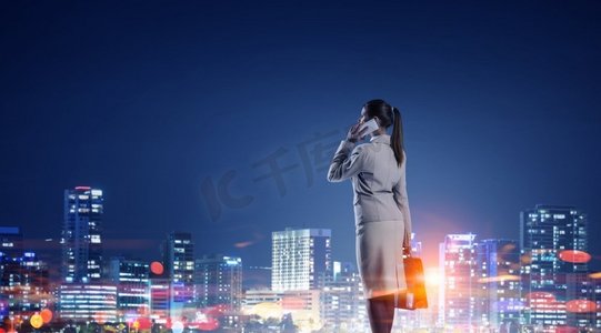 一直工作到深夜。有手机的年轻女实业家反对夜城市背景