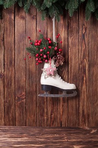 绿色圣诞装饰摄影照片_木质墙上挂着圣诞装饰的溜冰鞋。圣诞装饰溜冰鞋