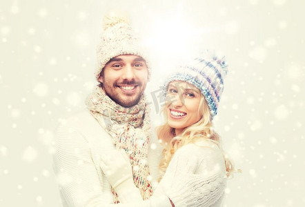 冬天，时尚，情侣，圣诞节和人的概念-戴着帽子和围巾微笑的男人和女人拥抱。一对穿着冬衣的微笑情侣拥抱着