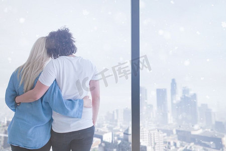 在寒冷的冬日里，浪漫幸福的年轻夫妇在家中靠窗喝着早晨的咖啡